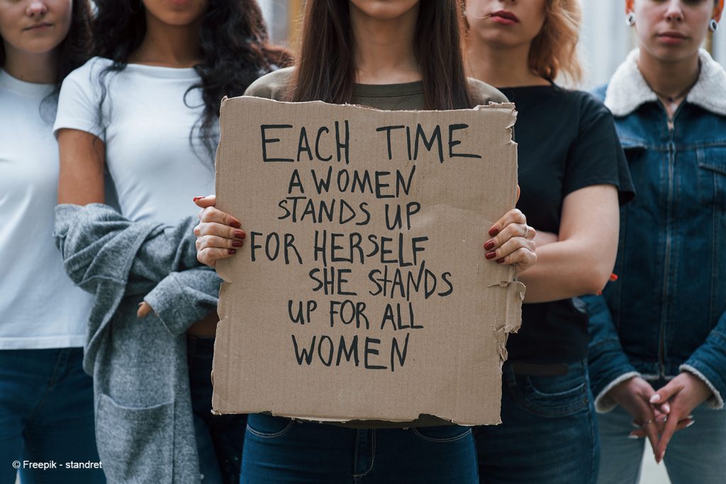 Konzentration vor einem Plakat. Eine Gruppe feministischer Frauen protestiert im Freien für ihre Rechte.
