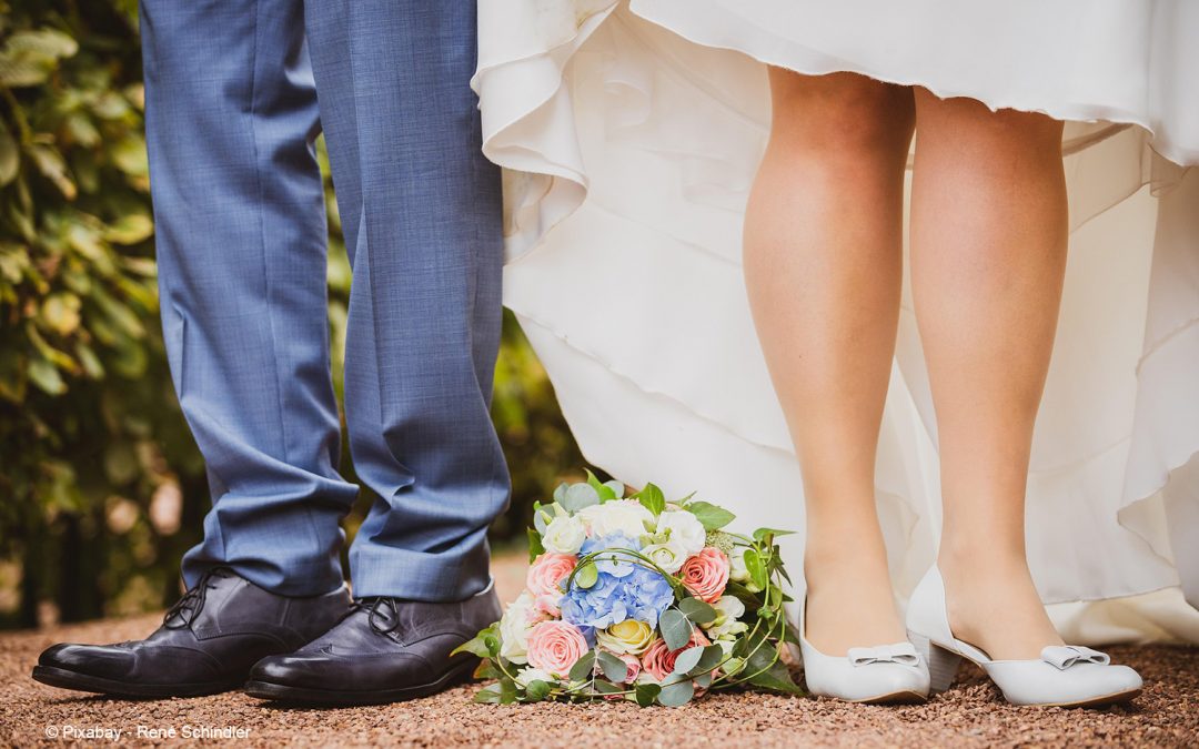 Braut und Bräutigam stehen nebeneinander. Es sind nur Füße und ein Blumenstrauß zu sehen.